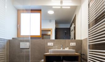 A modern bathroom with clean lines and bright light. It features an elegant sink unit and a glass shower cabin.