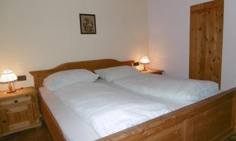 A cozy room with a wooden double bed. There is soft lighting and a tranquil atmosphere.