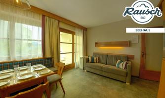 A cozy living room with a modern sofa and a dining area. Large windows provide plenty of natural light.