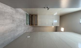 A modern shower area with bright, smooth tiles and a wooden shelf. The atmosphere is clean and inviting.