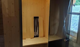 A modern sauna with wooden paneling and a glass front. Interior minimalist with a bench and space for towels.