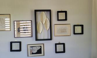 A decorative wall with various picture frames and artworks. The frames contain botanical motifs and short texts.