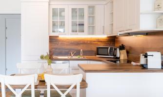 A modern kitchen with white cabinets and wood details. A table with chairs invites you to dine.