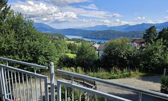 A beautiful view of a lake with mountains in the background. Above is a bright blue sky with a few clouds.