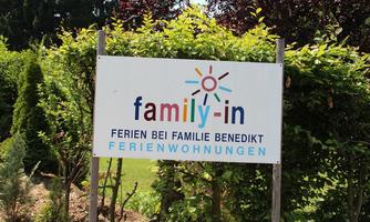 A sign reading "family-in" stands in front of a well-kept garden. It advertises holiday apartments with the Benedikt family.