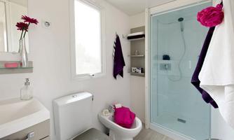 A modern bathroom with a shower and a toilet. The decoration includes towels and flowers in vibrant colors.