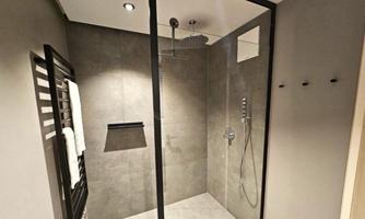 A modern shower with a glass wall and gray tiles. Towels hang on a towel warmer on the wall.