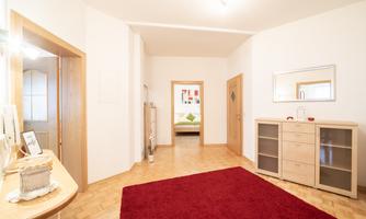 An inviting hallway with a red carpet and light-colored walls. In the background, additional rooms are visible.