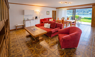 A bright and spacious holiday apartment with a red sofa and a view of a lake. The room is furnished in a modern and inviting style.