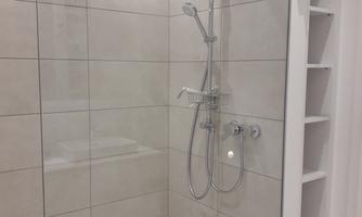 A modern shower with clear glass walls. The walls are brightly tiled, and the fittings appear contemporary.