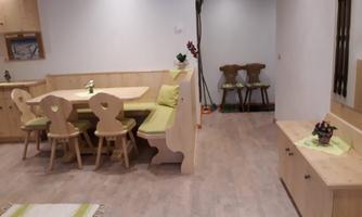 A bright and modern interior with a wooden dining table and chairs. In the background, additional seating and decorative elements can be seen.
