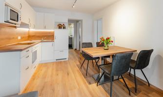 A modern kitchen with a dining table and chairs. The rooms are designed to be bright and welcoming.