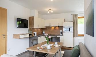Bright and modern kitchen with a dining area. The table is decorated with flowers and dishes.