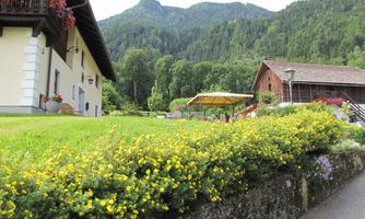 A picturesque landscape with a farmhouse and green hills in the background. Colorful flowers adorn the front yard, creating an inviting atmosphere.