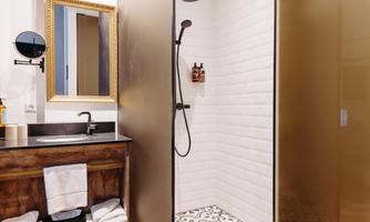 A modern bathroom with a walk-in shower and stylish tiles. The washing area is decorated with an elegant mirror and towels.