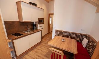 A modern kitchen with wooden details and a cozy seating area. The room is bright and invitingly designed.