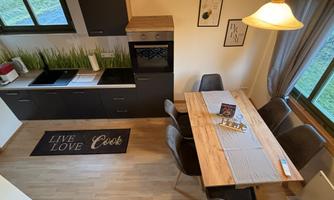 A modern kitchen with a large dining table and elegant chairs. The windows let in a lot of light and give the room an inviting atmosphere.