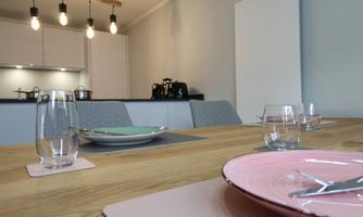 An inviting dining table set with plates and glasses. In the background, a modern kitchen can be seen.