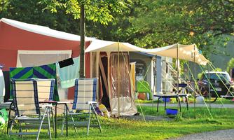 A peaceful campsite with several tents and sun loungers. Trees and green spaces surround the scene, ideal for a relaxing stay in nature.