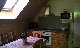 A bright kitchen with a skylight and wood paneling. A dining table with a tablecloth and modern kitchen equipment are visible.