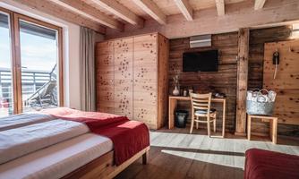A modern bedroom with wooden furniture and a large window. The decor is cozy and inviting.