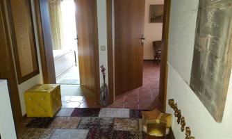 A hallway with two open doors leading to other rooms. Colorful carpets lie on the floor and a yellow stool is against the wall.