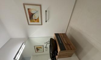 A modern bathroom with a stylish wooden vanity and a round sink. A colorful artwork hangs on the wall and the atmosphere is bright and inviting.