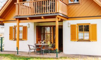 A charming house with a balcony and orange shutters. Outside, there is a table with chairs, perfect for sociable hours outdoors.