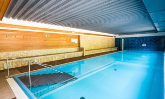 A modern swimming pool with clear water and wooden paneling. The atmosphere is relaxing and inviting.