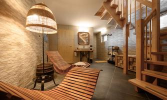 A relaxing room with wooden loungers and a modern lamp. The walls are painted in warm tones, creating a cozy atmosphere.