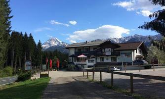 A cozy inn surrounded by trees and mountains. The snow-capped peaks are visible in the background.