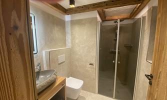 A modern bathroom with a shower cubicle and a stylish sink. The walls are in neutral colors, and wooden details add warmth to the space.