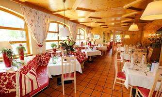 An inviting restaurant with wooden decor and cozy tables. Large windows let in plenty of daylight, creating a warm atmosphere.