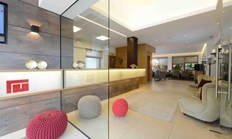 A modern foyer with glass walls and stylish furniture. Red and gray poufs add a splash of color.