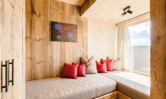 A cozy seating area with a wooden design. The windows let in plenty of light, and the red cushions create an inviting atmosphere.
