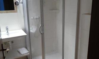 A modern bathroom with a glass shower and a sink. The walls are tiled in light colors and there is an intimate atmosphere.