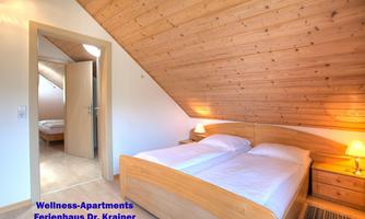 A cozy bedroom with a double bed and wooden paneling. The room is bright and has an inviting atmosphere.