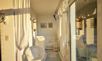 A bright, inviting room with large windows and comfortable furniture. The atmosphere is friendly and bathed in light.