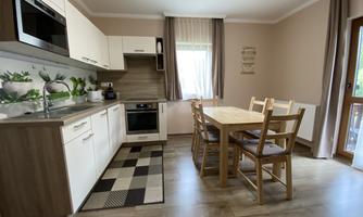 A modern kitchen with bright furniture and a large dining area. The space is well-lit and has a cozy atmosphere.