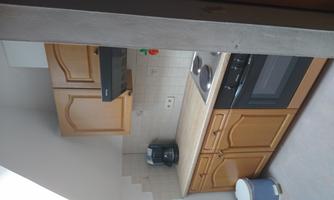 A small kitchen with wooden-colored cabinets and modern appliances. The room is bright and well-organized.