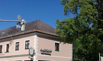 A cozy inn with a clear blue sky in the background. Next to the building stands a large tree.