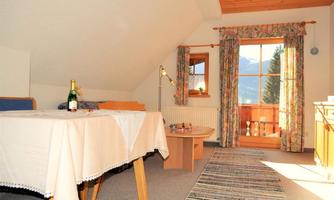 A cozy room with skylights and wooden ceilings. On the table is a bottle of sparkling wine, and the view looks out to the mountains through the window.