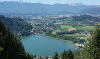A picturesque landscape with a clear lake and green meadows. In the background, majestic mountains rise under a blue sky.