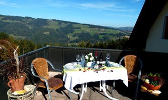 A beautifully set table on a terrace with a view of the hills. The surroundings are green and sunny, ideal for a relaxed meal outdoors.