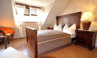 A cozy bedroom with a large bed and two nightstands. The warm wooden tones and soft light create an inviting atmosphere.