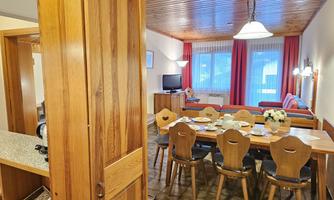 A cozy apartment with a dining area and a living room. The combination of wood and light furnishings creates an inviting atmosphere.