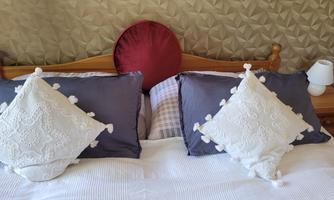 A cozy bed with two decorative pillows and a round headboard. The walls are adorned with a modern, textured pattern.