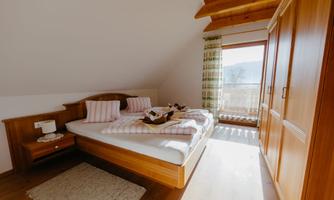 A bright bedroom with wooden furniture and two beds. A window offers a view of the mountains and lets in plenty of light.