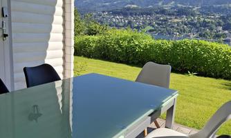 A stylish table on a terrace, surrounded by modern chairs. In the background, a beautiful mountain landscape stretches out.