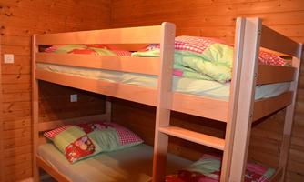 A cozy sleeping area with a wooden bunk bed. The beds are decorated with colorful pillows and blankets.